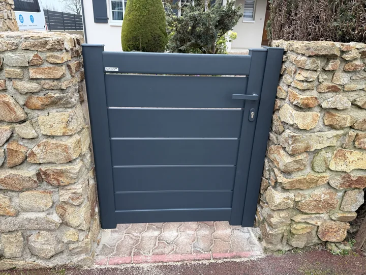 Portillon anthracite entre murs en pierre — vue 1